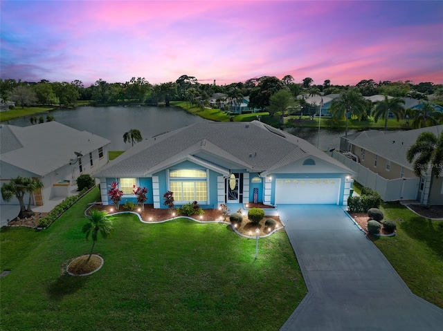 single story home featuring a garage, a water view, and a yard