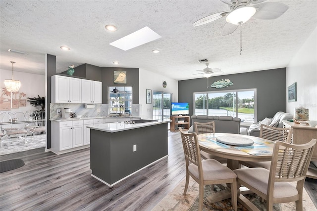 kitchen featuring a skylight, white cabinetry, tasteful backsplash, dark wood-type flooring, and hanging light fixtures