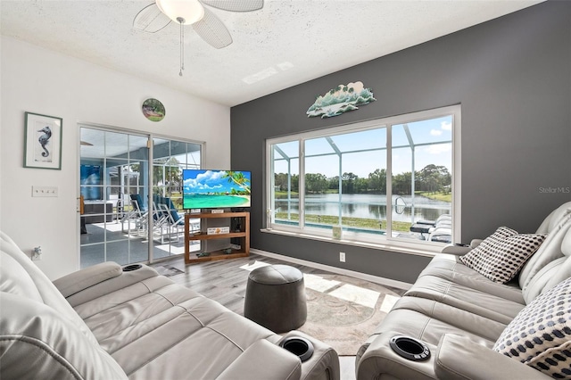 living room with a textured ceiling, ceiling fan, and wood-type flooring