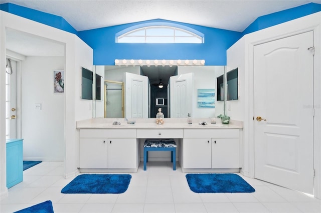 bathroom with a shower with shower door, tile patterned flooring, a textured ceiling, vaulted ceiling, and vanity