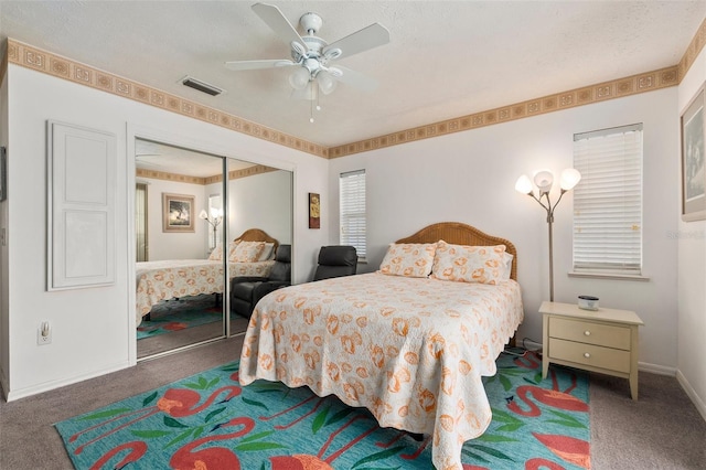 bedroom with ceiling fan, a closet, a textured ceiling, and dark colored carpet