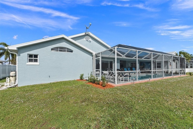 back of house with glass enclosure, a yard, and a patio