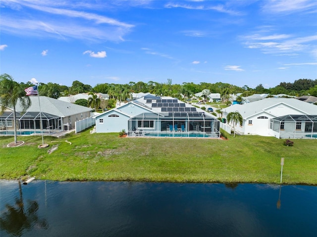 rear view of house featuring a water view, a yard, solar panels, and glass enclosure