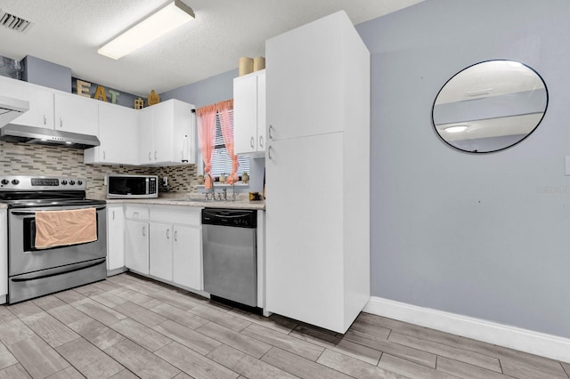 kitchen featuring a textured ceiling, white cabinets, appliances with stainless steel finishes, sink, and backsplash