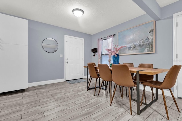 dining space featuring a textured ceiling and light wood-type flooring