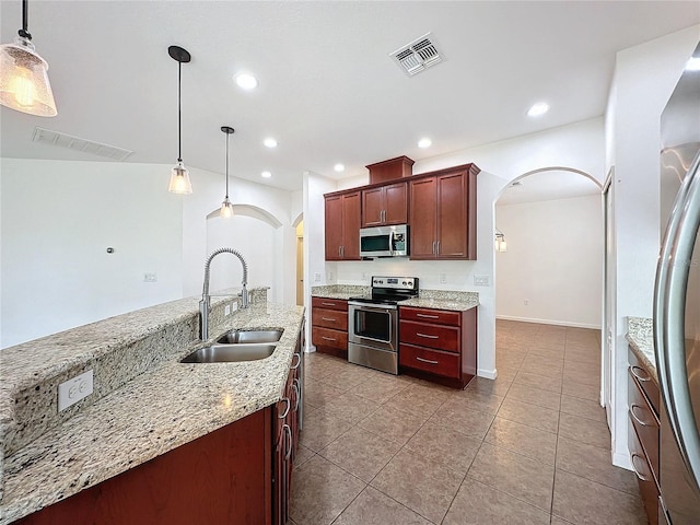 kitchen with arched walkways, stainless steel appliances, visible vents, hanging light fixtures, and a sink