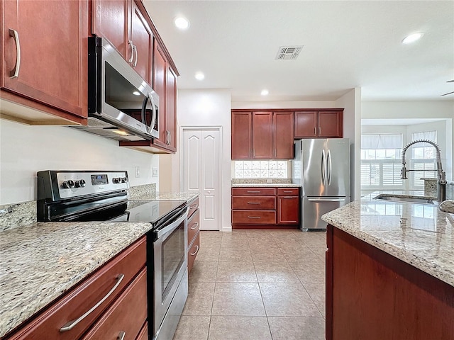 kitchen featuring light stone counters, light tile patterned floors, visible vents, appliances with stainless steel finishes, and a sink