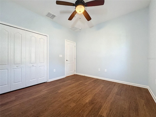 unfurnished bedroom with dark wood-style floors, a closet, visible vents, and baseboards