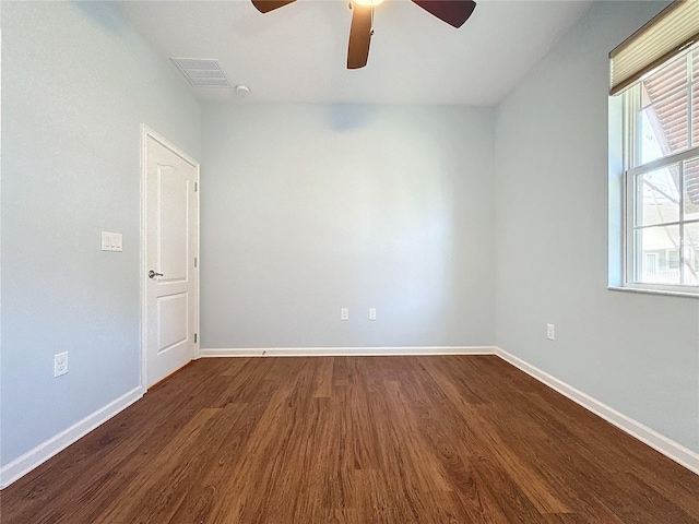 empty room featuring visible vents, baseboards, ceiling fan, and dark wood-style flooring