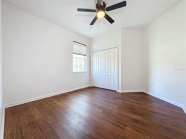 unfurnished bedroom with a ceiling fan, a closet, baseboards, and dark wood-type flooring