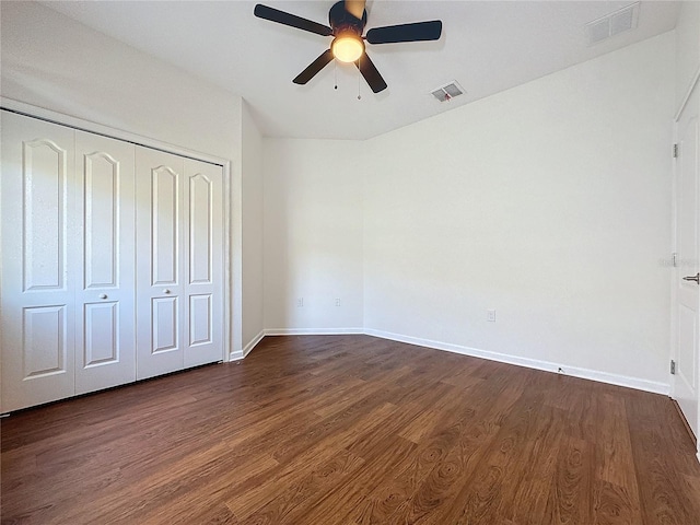 unfurnished bedroom with dark wood-style floors, baseboards, visible vents, and a closet