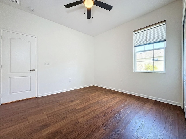 unfurnished room featuring ceiling fan, dark wood-type flooring, visible vents, and baseboards