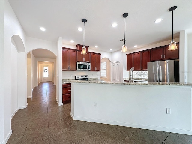 kitchen featuring stainless steel appliances, light stone countertops, and pendant lighting