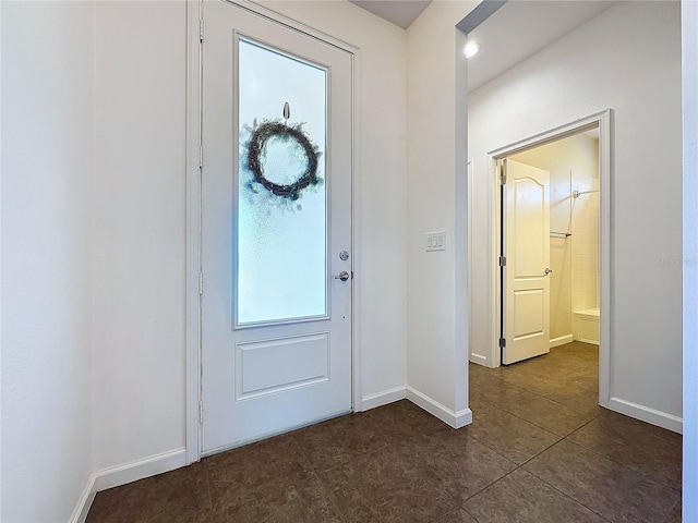 entrance foyer with dark tile patterned floors and baseboards