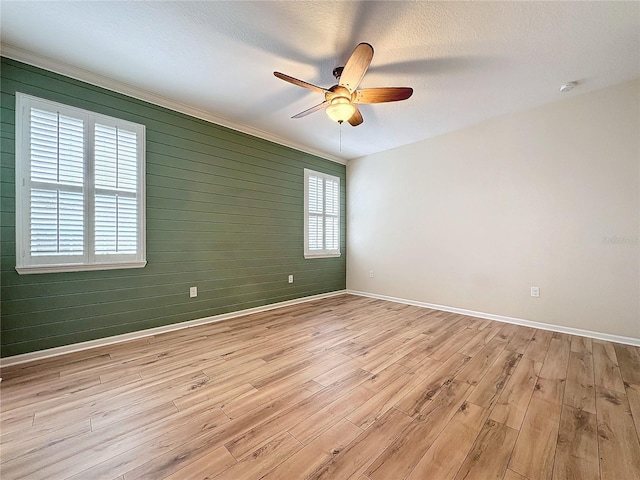 empty room with a textured ceiling, light wood finished floors, a ceiling fan, and baseboards