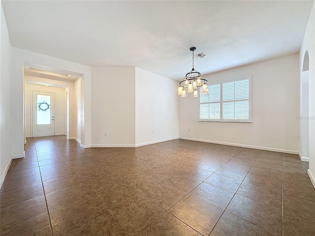 unfurnished room featuring a chandelier, dark tile patterned flooring, visible vents, and baseboards