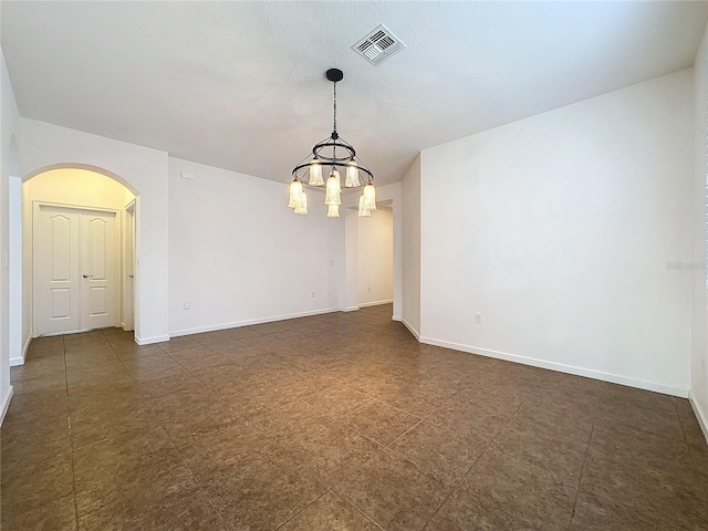 spare room with baseboards, visible vents, and arched walkways