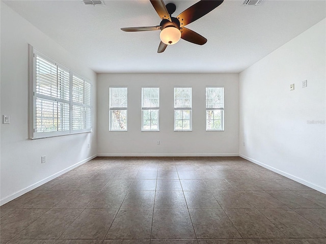 unfurnished room featuring visible vents, baseboards, and dark tile patterned flooring