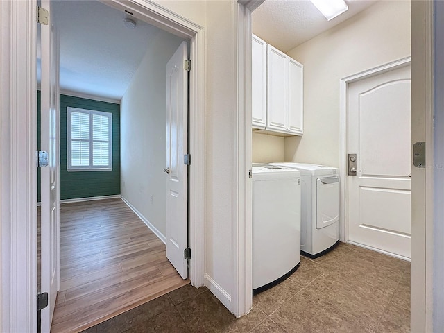 laundry room with cabinet space, baseboards, a textured ceiling, and independent washer and dryer