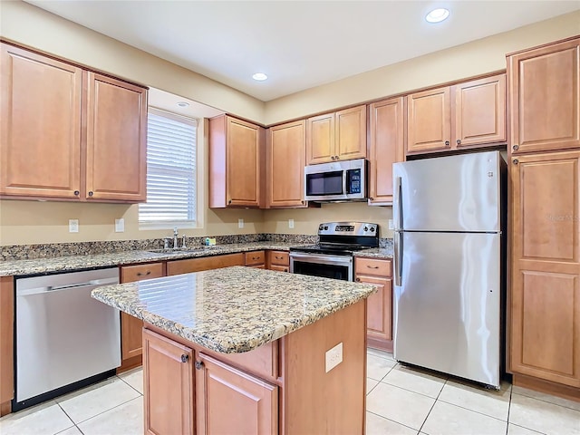 kitchen featuring a center island, sink, light stone countertops, stainless steel appliances, and light tile patterned floors