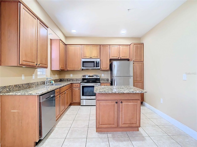 kitchen featuring light tile patterned floors, appliances with stainless steel finishes, a kitchen island, and light stone countertops