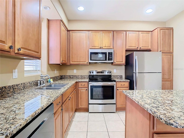 kitchen featuring light tile patterned flooring, light stone countertops, stainless steel appliances, and sink