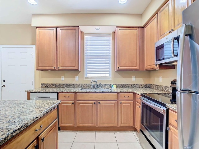 kitchen with light stone countertops, appliances with stainless steel finishes, sink, and light tile patterned flooring