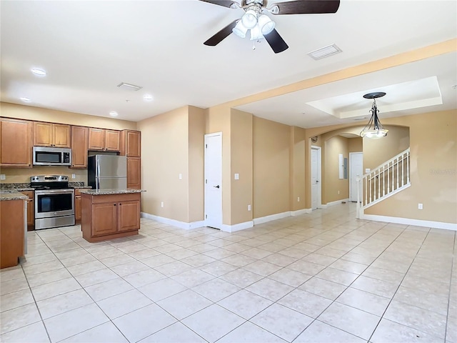 kitchen featuring light stone countertops, pendant lighting, a center island, and stainless steel appliances