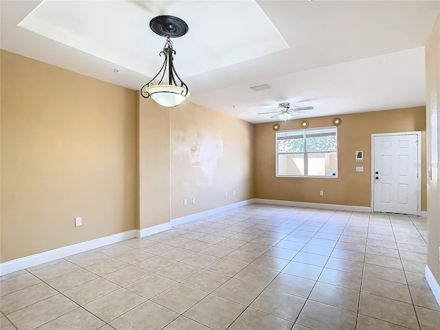 tiled spare room with ceiling fan and a tray ceiling