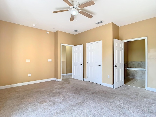 unfurnished bedroom featuring ceiling fan, ensuite bath, and light carpet