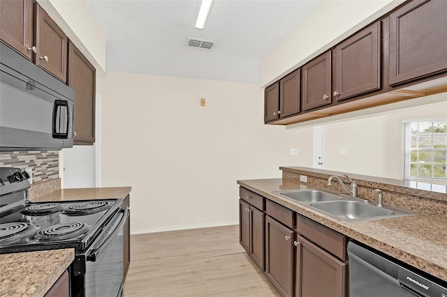 kitchen featuring sink, backsplash, light hardwood / wood-style floors, black appliances, and dark brown cabinetry