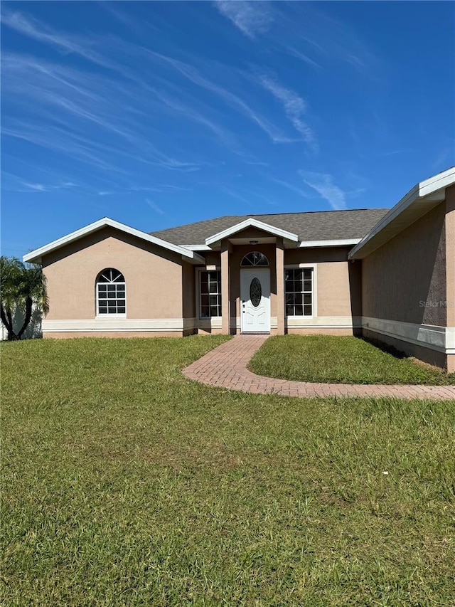 view of front of property featuring a shingled roof, a front yard, and stucco siding