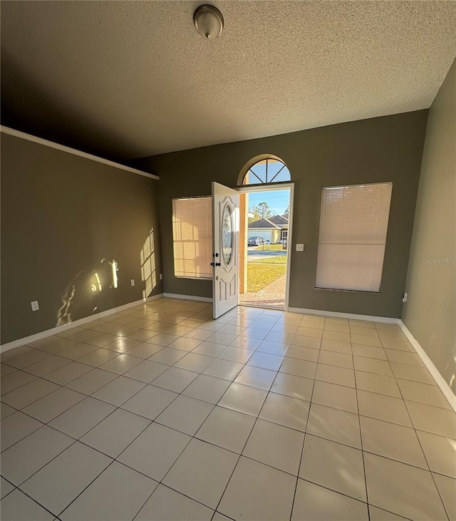 spare room with a textured ceiling and light tile patterned flooring