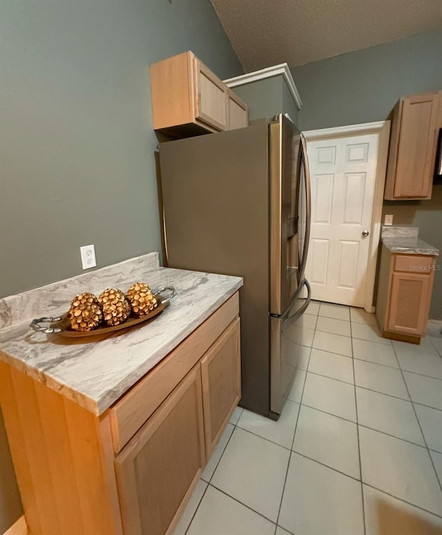 kitchen with light tile patterned floors, stainless steel fridge, and light brown cabinets