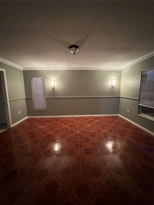 unfurnished room featuring a textured ceiling, baseboards, and dark tile patterned floors