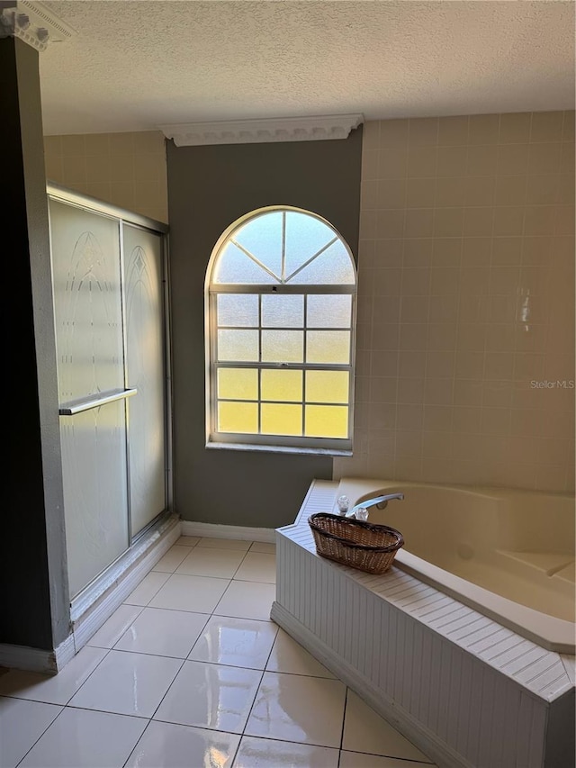 bathroom featuring a stall shower, tile patterned floors, a textured ceiling, and a bath