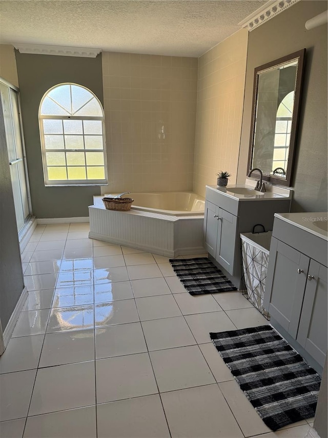 bathroom with two vanities, a sink, a textured ceiling, tile patterned flooring, and a bath