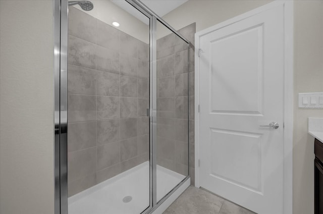 bathroom featuring tile patterned floors, an enclosed shower, and vanity