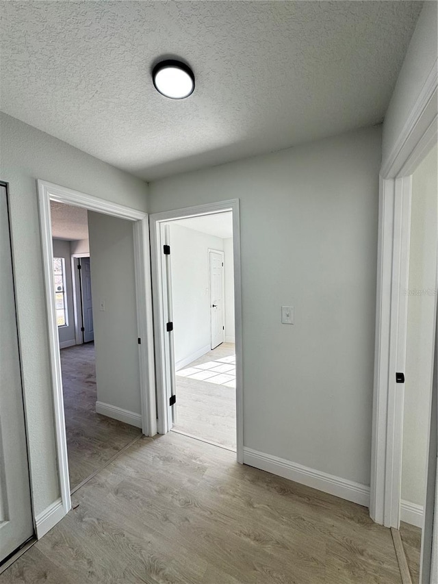 hall featuring light hardwood / wood-style floors and a textured ceiling