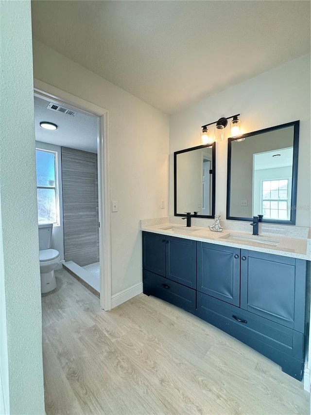 bathroom with hardwood / wood-style flooring, vanity, walk in shower, and toilet