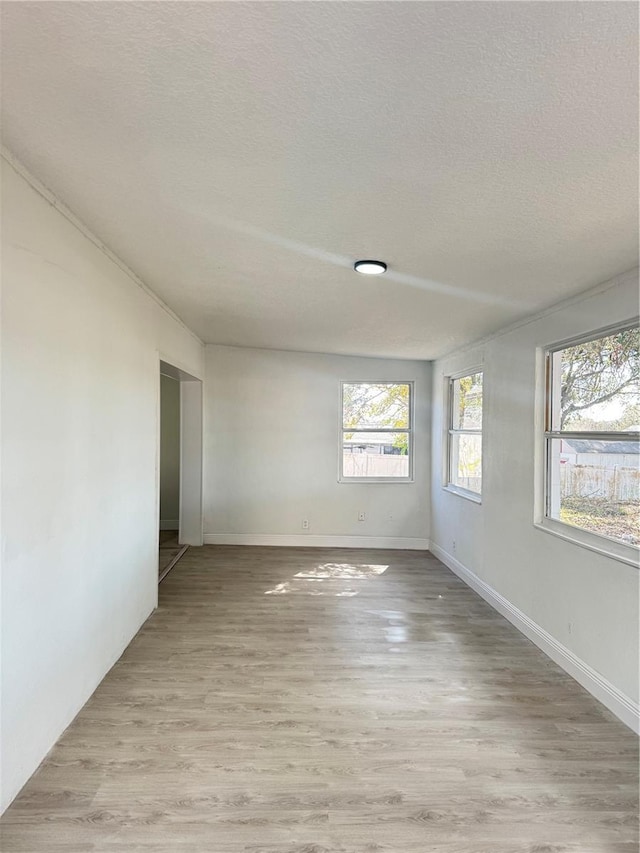 spare room featuring a textured ceiling and light hardwood / wood-style flooring