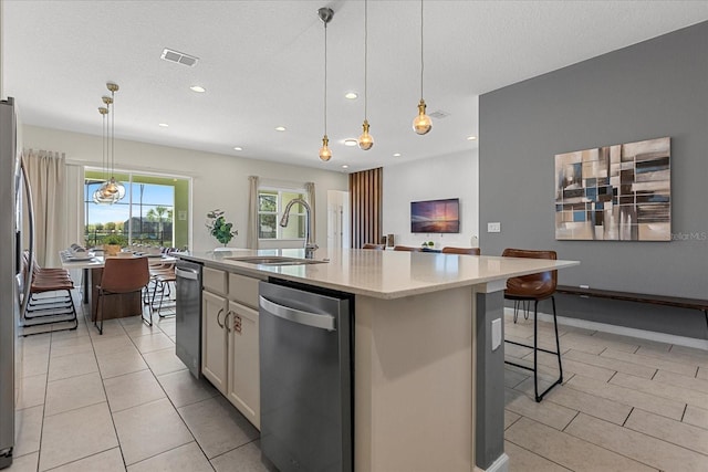 kitchen featuring sink, hanging light fixtures, a breakfast bar, stainless steel dishwasher, and a center island with sink