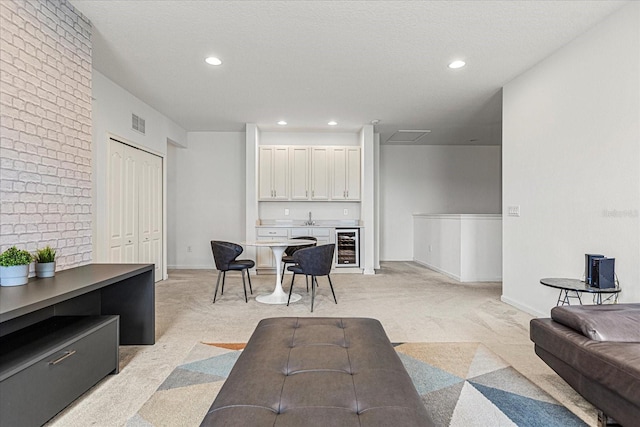 carpeted living room with a textured ceiling, beverage cooler, and indoor wet bar