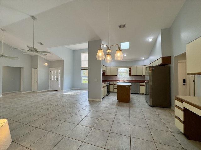 kitchen featuring stainless steel appliances, high vaulted ceiling, light tile patterned floors, and cream cabinets