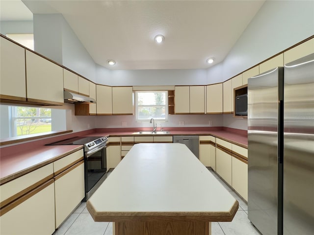 kitchen with sink, appliances with stainless steel finishes, cream cabinetry, and a kitchen island