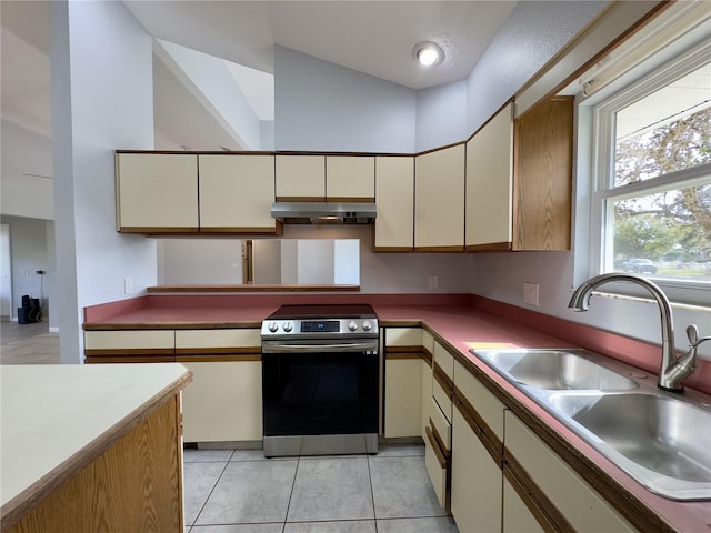 kitchen featuring stainless steel range with electric stovetop, cream cabinets, light tile patterned floors, and sink