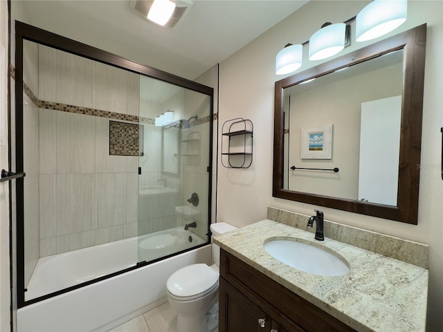 full bathroom with enclosed tub / shower combo, vanity, and toilet