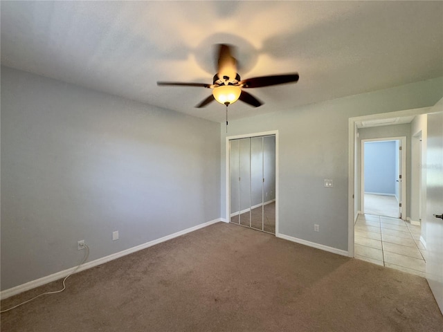 unfurnished bedroom featuring ceiling fan, light colored carpet, and a closet