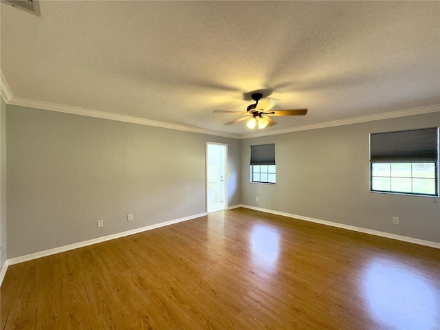 spare room featuring ceiling fan, dark wood-type flooring, a wealth of natural light, and crown molding