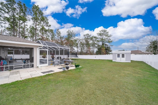 view of yard with a storage shed, a patio area, and glass enclosure